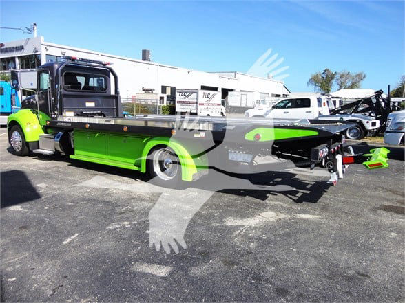 2022 Peterbilt 337 tow truck with bright green chassis and black flatbed, side view showing rear towing apparatus and wheel covers.