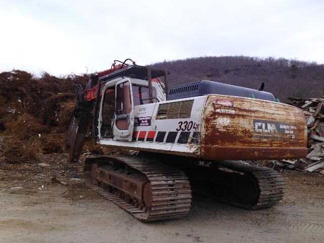 Link-Belt 330LX excavator in-service with tracked undercarriage and visible hydraulic arm, labeled 330LX on side, rust and wear on rear counterweight.