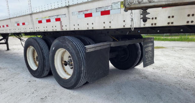 Trailer undercarriage showing dual rear axles with tires and mud flaps on a Vanguard VXP trailer.