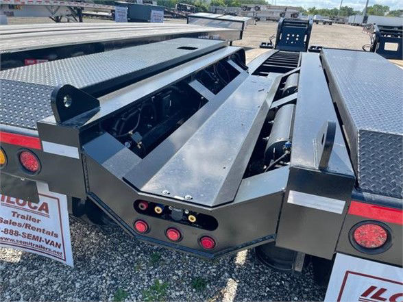 Lowboy trailer deck with folded ramps and starboard side storage, 2023 Fontaine 55 ton steel lowboy rear view showing deck surface and support brackets.