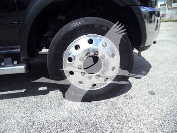 Truck wheel and tire close-up showing chrome steel wheel with lug nuts and black tire. Fender and step rail visible in background.