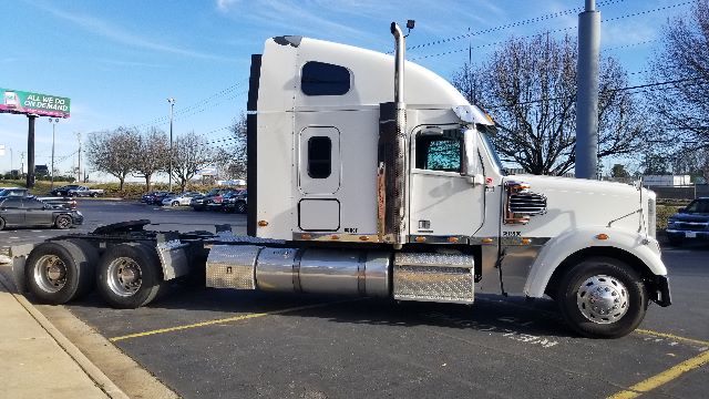 Truck: 2013 Freightliner Coronado 132 sleeper cab, side view showing fuel tanks, exhaust stacks, and dual rear axles.