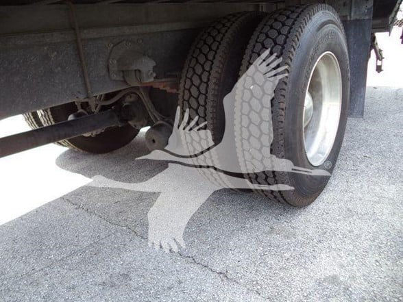 Rear dual tires of a truck tractor showing suspension components and leaf spring undercarriage.