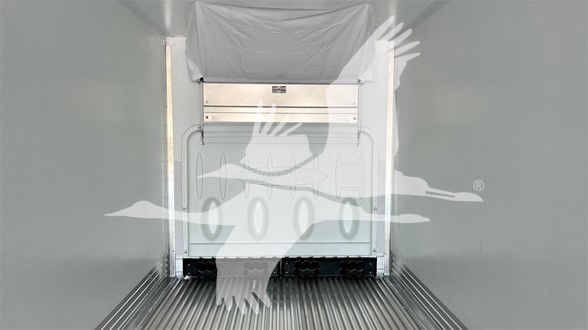 Trailer rear interior showing cargo area with metal walls and ribbed floor in a refrigerated trailer, rear door closed.