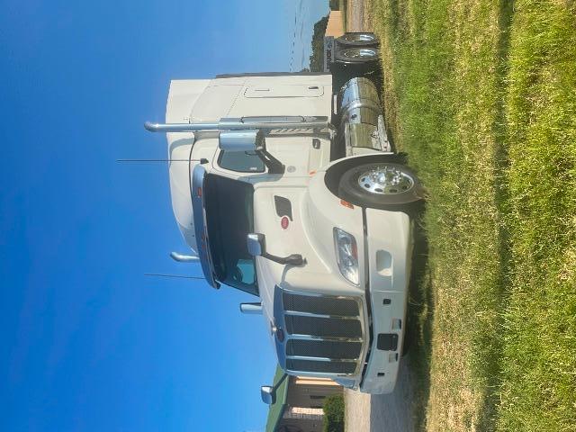 Peterbilt 579 conventional sleeper truck side view with white paint and chrome exhaust stacks.