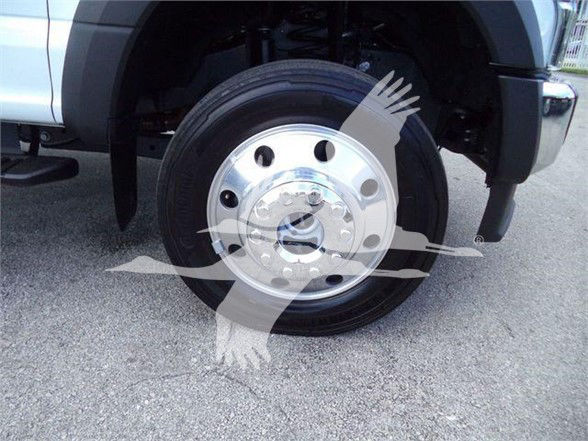 Front wheel of a 2022 Ford F550, chrome hubcap and black tire visible, wheel well and fender with part of the truck body.