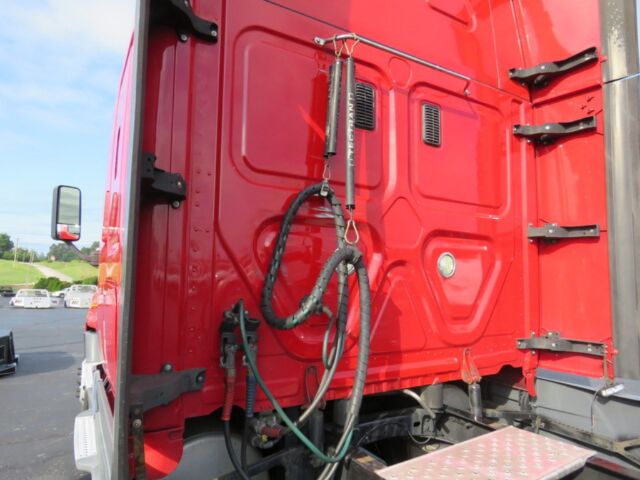 Rear of red Freightliner Cascadia Evolution truck cab with hoses and connectors visible, vertical door handle, and metal step at bottom.