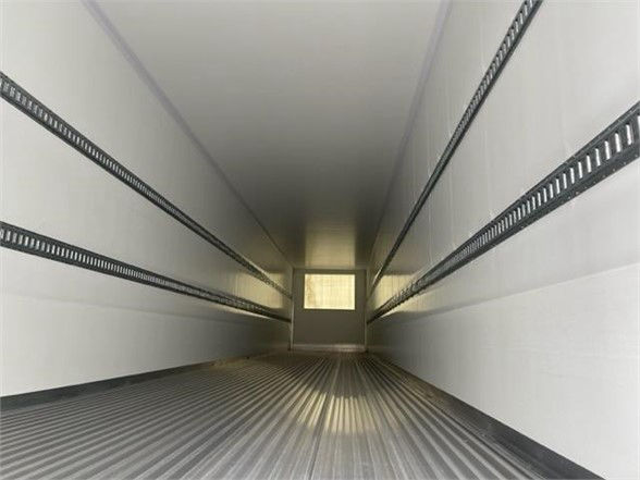 Inside of a CIMC Cool Globe reefer trailer with empty interior, viewing from rear toward the front, corrugated metal floor and white walls.