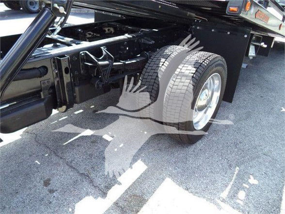 Truck rear wheel and chassis undercarriage with dual tires and suspension components visible.