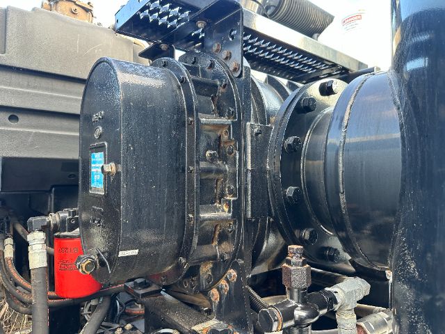 Freightliner M2 vacuum truck engine bay showing large black compressor housing, blue tag, red component, hoses, and metallic fittings.
