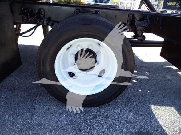 Ford F650 wheel and undercarriage view showing white steel wheel with tire; part of chassis and suspension visible.