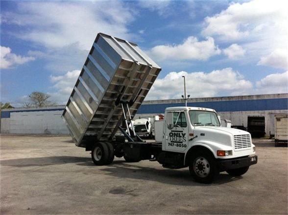 Dump truck with raised dump body on a white cab, 16 ft Advanced Fabricators dump body trailer, blue sky with clouds.