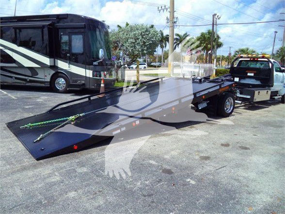 2023 Chevrolet Silverado 6500HD flatbed tow truck in dealership lot with RV in background.