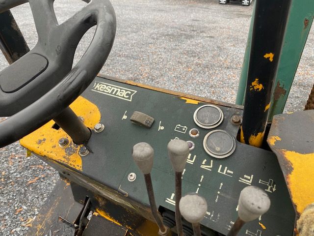 Kesmac F5000 forklift control panel with steering wheel and multiple levers, showing faded labels and round gauges.