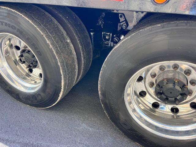 Dual rear wheels on a Peterbilt truck trailer, with chrome rims and visible tire treads; part of suspension and frame visible between wheels.