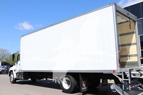 Truck cab and chassis with a large box cargo area, side view, Hino logo not visible, empty interior of box visible at rear.