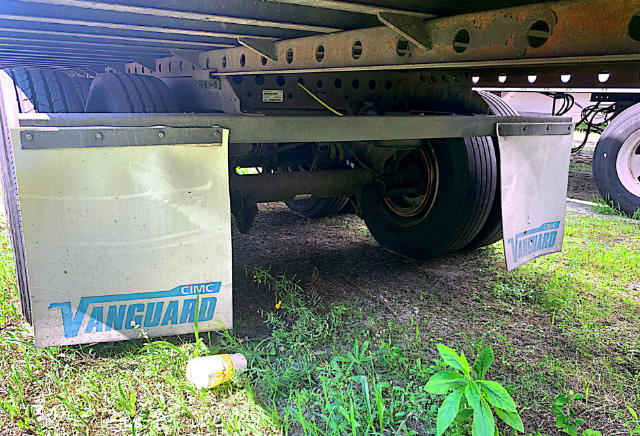 Trailer underside showing Vanguard mud flaps with blue Vanguard logos, wheels, and suspension components visible under the frame.