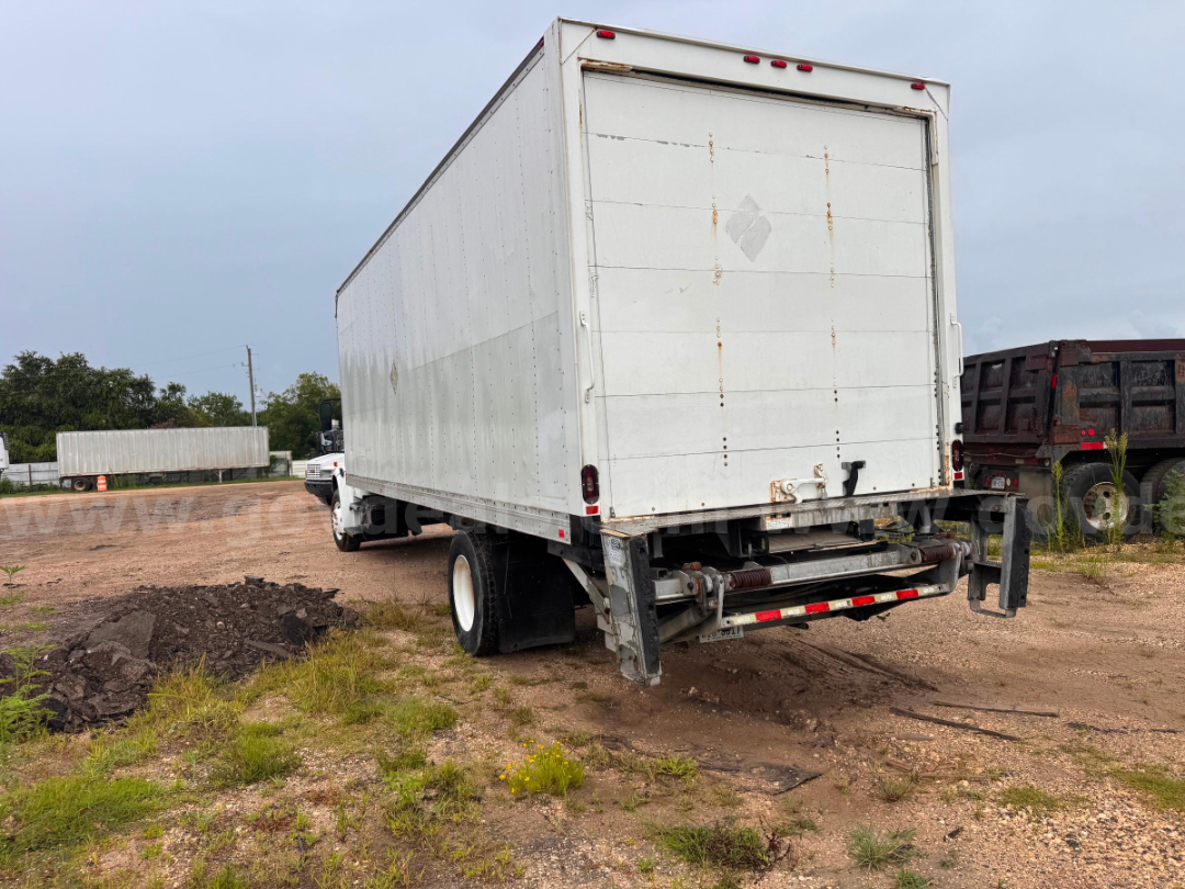 Box truck rear showing cargo box and rear underride guard; white exterior, Freightliner M2 106 style, dual rear wheels, loading doors closed.