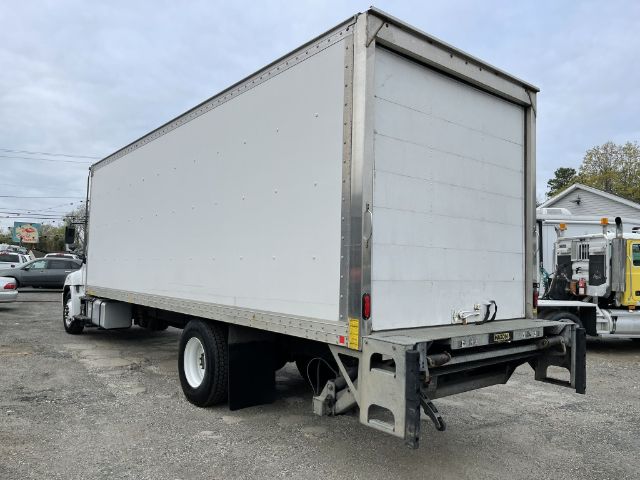 Box truck rear/side view with a white cargo box on a chassis. Visible are the rear doors, undercarriage, and spare wheel well. No readable text visible on signs.