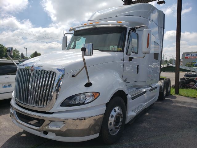 International ProStar tractor-trailer cab in white with chrome grille, large side mirrors, and sleeper cab; front bumper and fenders chrome accented.