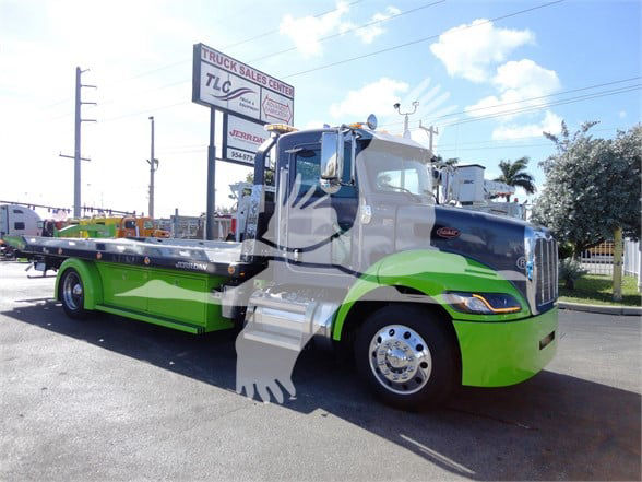 Peterbilt 337 tow truck in green and silver color scheme, side view showing tow bed.