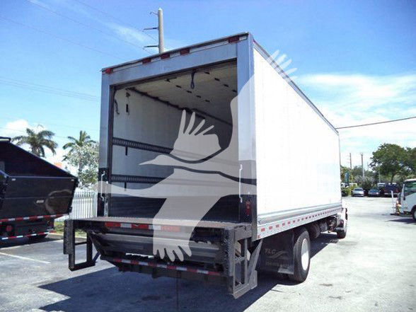 Truck trailer with rear doors open, white refrigerated box truck in a lot.