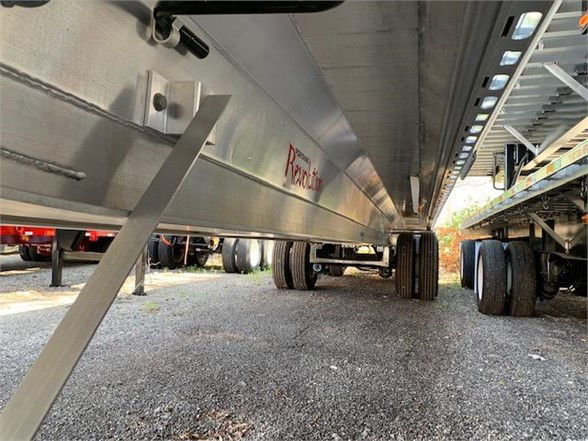 Aluminum flatbed trailer undercarriage showing wheels and frame with 'Redline' branding on side.