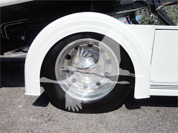 Wheel and front fender of a white 2022 Hino 268A tow truck showing polished aluminum wheel and tire.