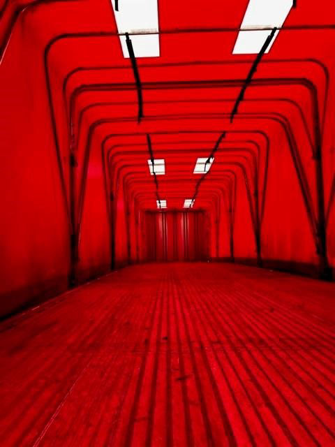 Interior view of a red curtain-side trailer with a long, enclosed loading space.