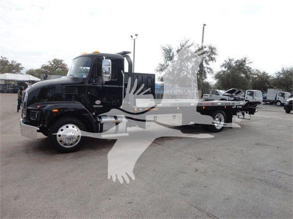 2023 Mack MD6 tow truck with black cab, flatbed, front chrome bumper, and large side mirrors.
