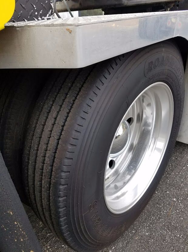 Truck wheel and dual tire setup on a Peterbilt 389 axle with polished aluminum rim and Roadmaster tire; visible fender and step surface above wheel.