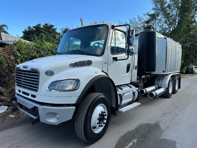 Freightliner M2 vacuum truck in white, front-left view, with large cylindrical tank, side steps, and dual rear axles.