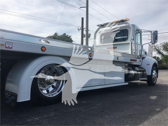 2022 Peterbilt 337 tow truck side view showing cab, flatbed, chrome wheels, and side steps.