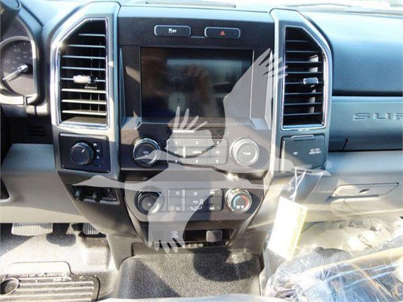 Dashboard of a Ford truck interior showing center touchscreen, HVAC controls, and steering area. Visible text includes 'FORD' badge area on the dashboard and faint 'SUPER DUTY' lettering on the passenger side near the glove compartment.