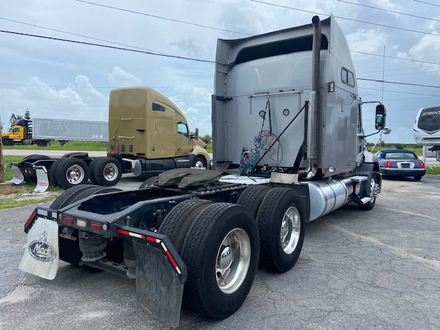 Truck chassis of a 2010 Mack CXU613 conventional sleeper showing rear view with dual rear axles and fifth wheel combined with side fuel tanks.