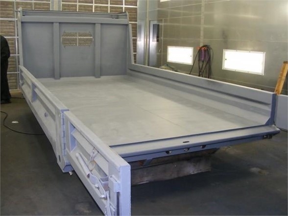 A 14 ft dump body trailer bed from Advanced Fabricators with tall side rails and rear access gate, in a workshop.