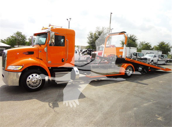 Orange 2022 Peterbilt 337 tow truck with flatbed in a dealership lot.