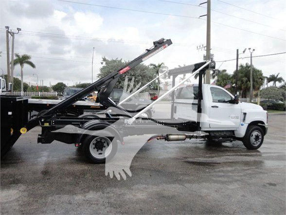2023 Chevrolet Silverado 5500HD tow truck with a hydraulic wheel-lift and tilt bed, white cab, stock number SIL550014SNG visible on listing overlay.