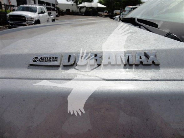 Vehicle rear with Duramax badge and Allison Transmission emblem on tailgate, Silverado 6500HD flatbed truck.
