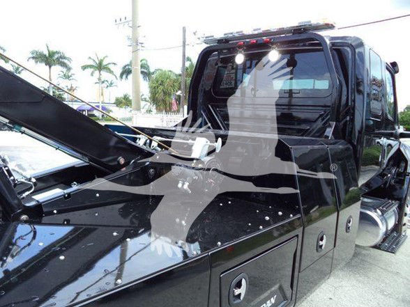 Truck cab interior and front hood area showing black International MV truck with open hood. Visible text: none clearly legible on components.