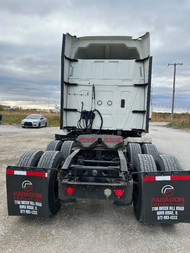 Truck tractor rear view showing fifth-wheel coupling and Paragon Freight mudflaps with text.