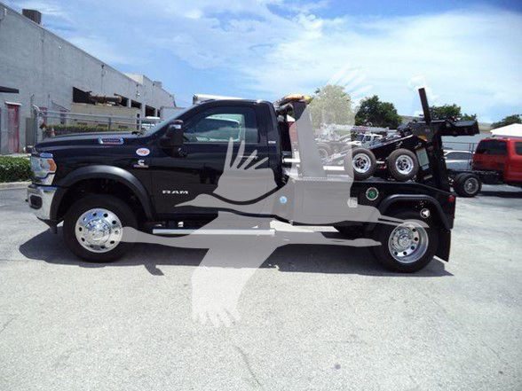 Ram 5500 tow truck side view showing cab and flatbed with wheel rims, side mirrors, and front fender badge. Visible text includes RAM on front door and RAM emblem; no other legible markings.