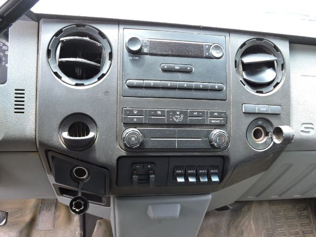 Dashboard of a 2016 Ford F350 crew cab utility truck showing central radio and climate controls, circular air vents, auxiliary switches, and ignition with key inserted.