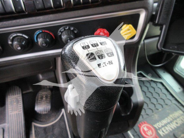 Truck gear shifter with E-T-N hub indicators and green, red, and yellow controls in dashboard area; foot pedals visible.