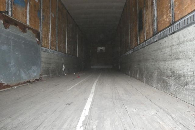 Trailer interior showing long empty cargo area with wooden side walls and metal floor and a white center line.