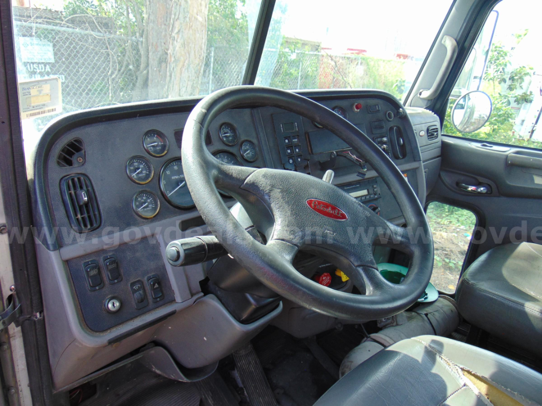 Cockpit of a 2013 Peterbilt 365 cab, steering wheel with Peterbilt emblem, dashboard gauges, and driver seat visible.