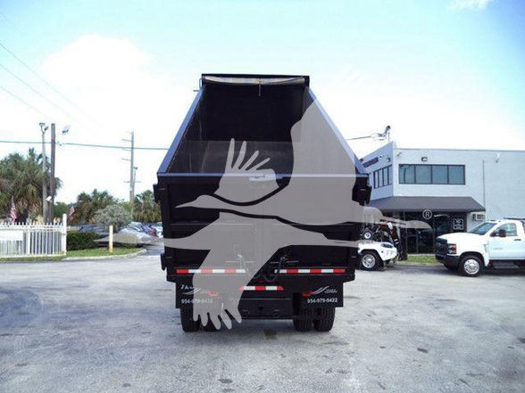 Rear view of a dump truck bed on a 2019 International DURASTAR 4300 with stock number T18699FM dealership lot in background.