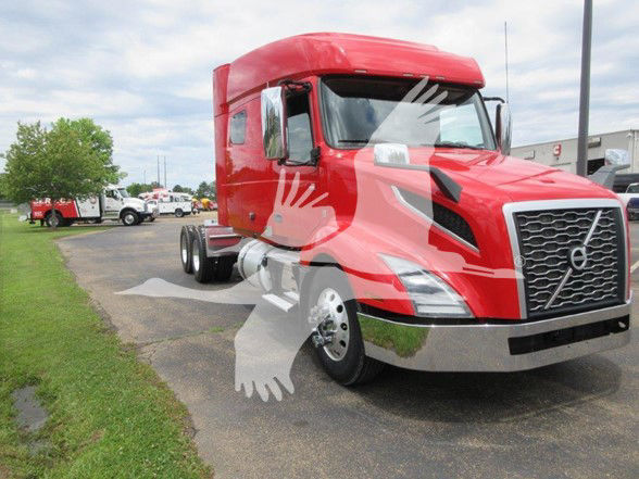 Volvo VNL64T740 truck in red with sleeper cab and chrome bumper, parking lot background.