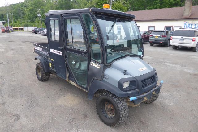 Club Car Carryall 1700 utility vehicle with enclosed cab and cargo box, gray body, off-road tires, and orange beacon on roof; visible VIN SD1749-839137 and stock sticker.