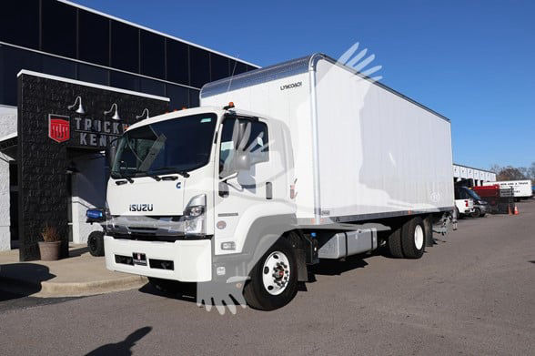 Isuzu FTR box truck in a dealership lot. Cab shows Isuzu badge, white color, box body with Linup? lettering on side. Open area around the cab.